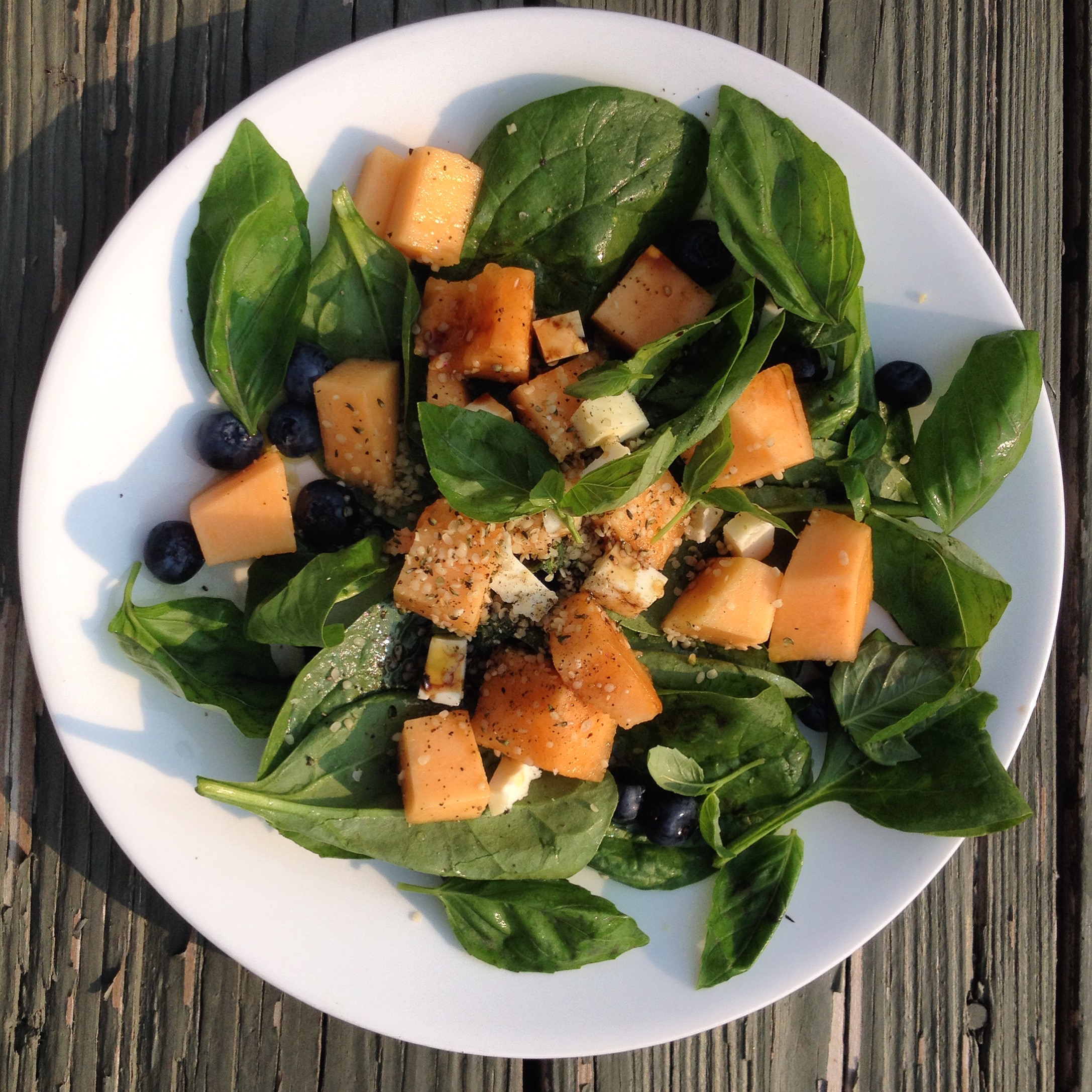 Displaying an image of cantaloupe salad with spinach and blueberries.